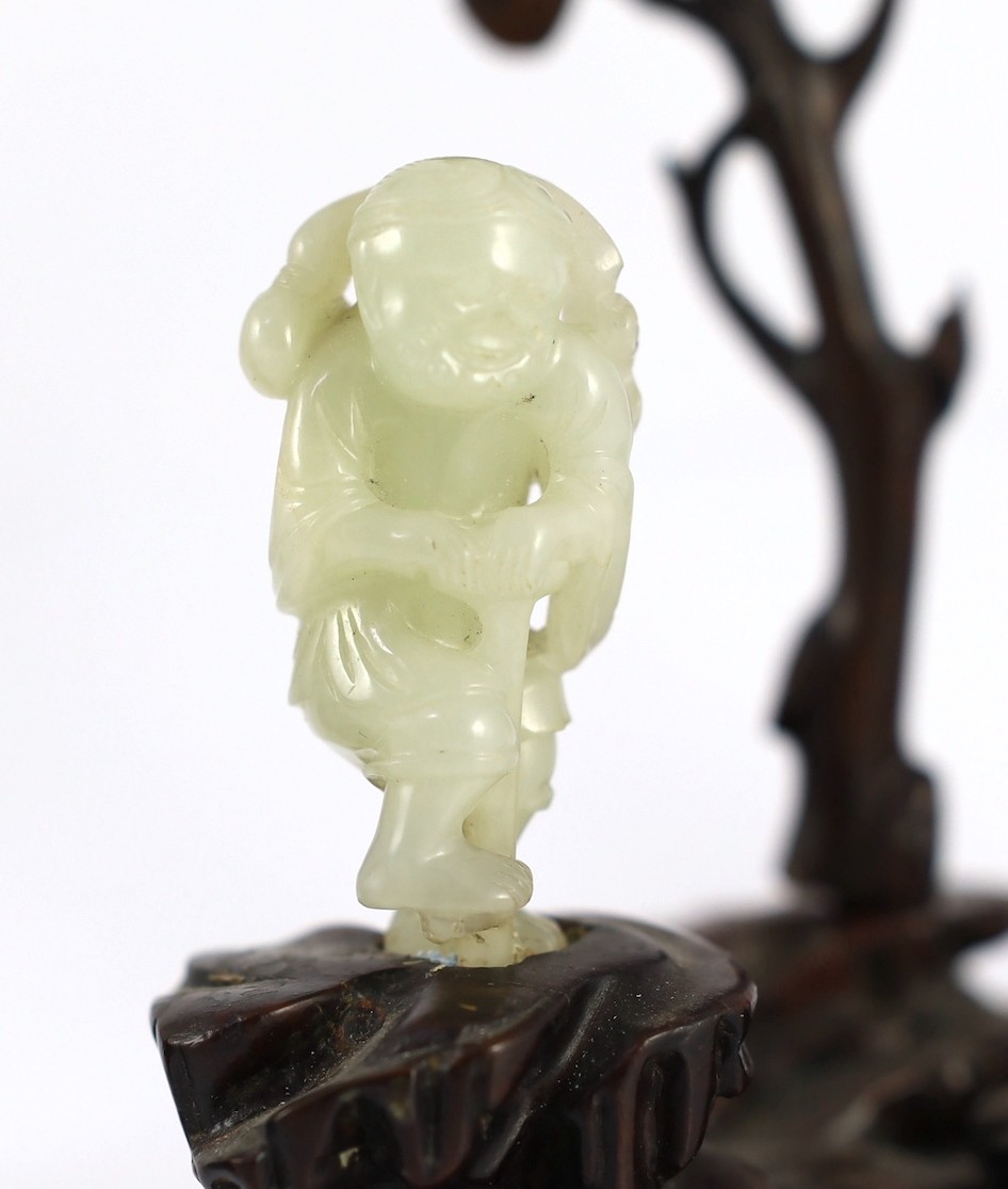 An assembled group of four Chinese pale celadon jade figures, 18th/19th century, displayed on two later wood 'rock-work' stands, total height approximately 19cm high